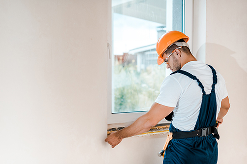 Carpenter from Tampa FL Measuring Wall Where Residential Impact Replacement Windows Will Be Installed